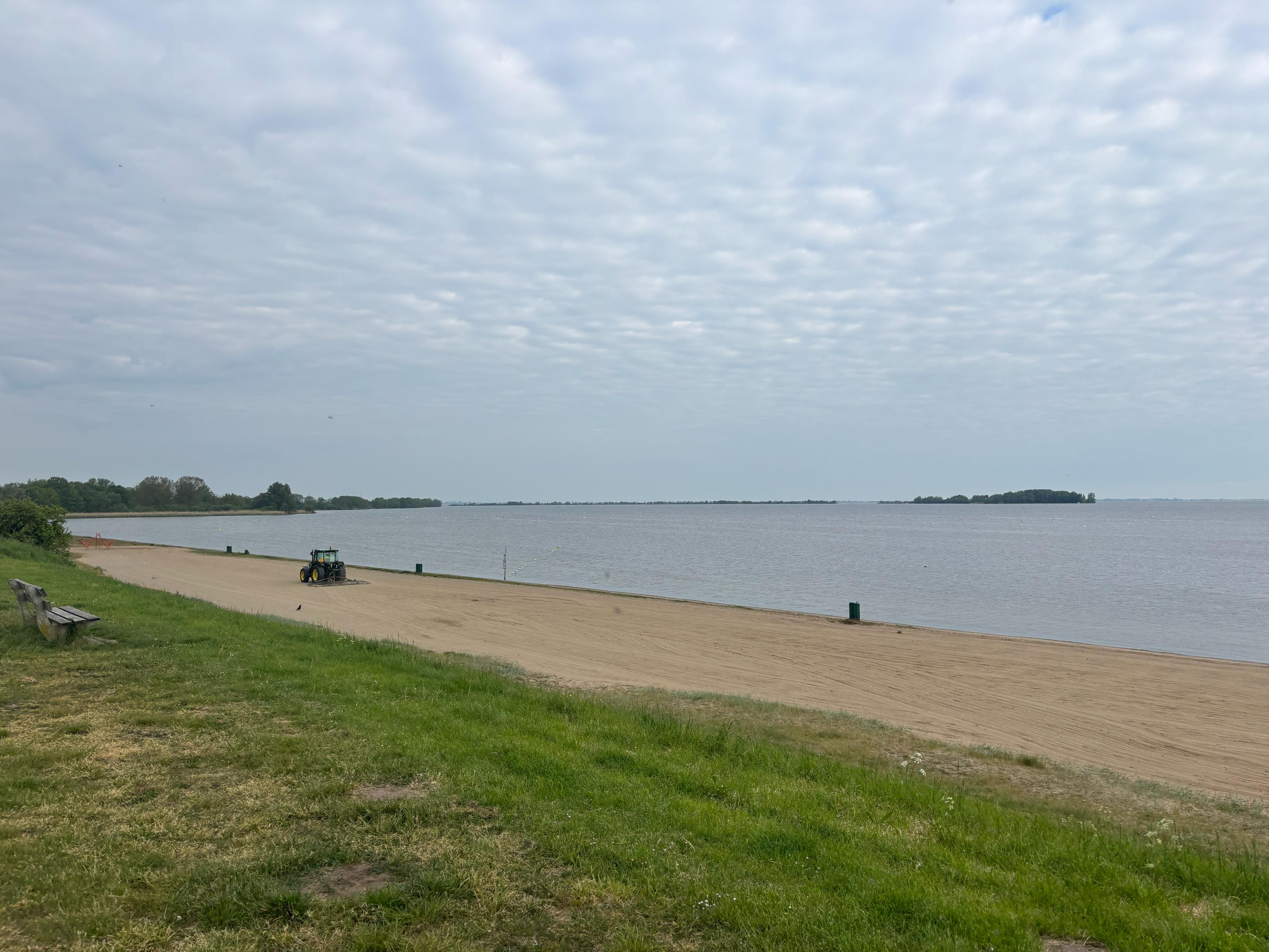 Het pas geveegde strand van Muiderberg in de ochtend, met de tractor van de Stichting.